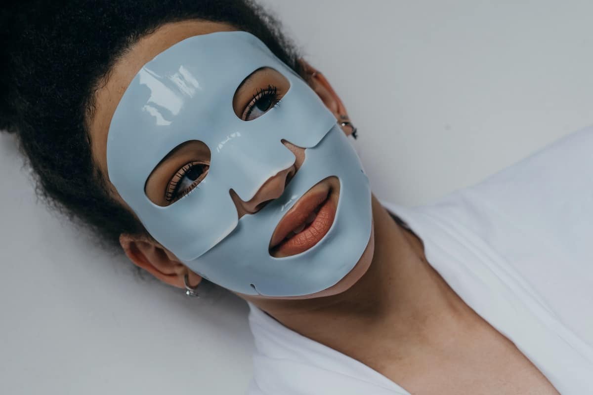woman practicing self-care wearing a sheet mask